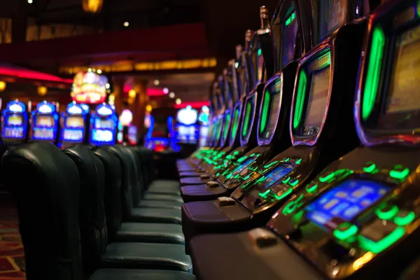Một cô gái trong bộ váy xanh sang trọng đứng cạnh vòng roulette, gợi lên bầu không khí casino cao cấp của MOBIMEG.