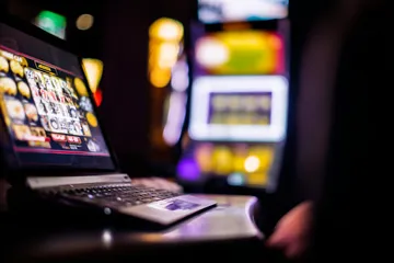 Một cô gái mỉm cười bên cạnh các máy slot sáng rực với biểu tượng may mắn, thể hiện danh mục slot nổi bật của MOBIMEG.